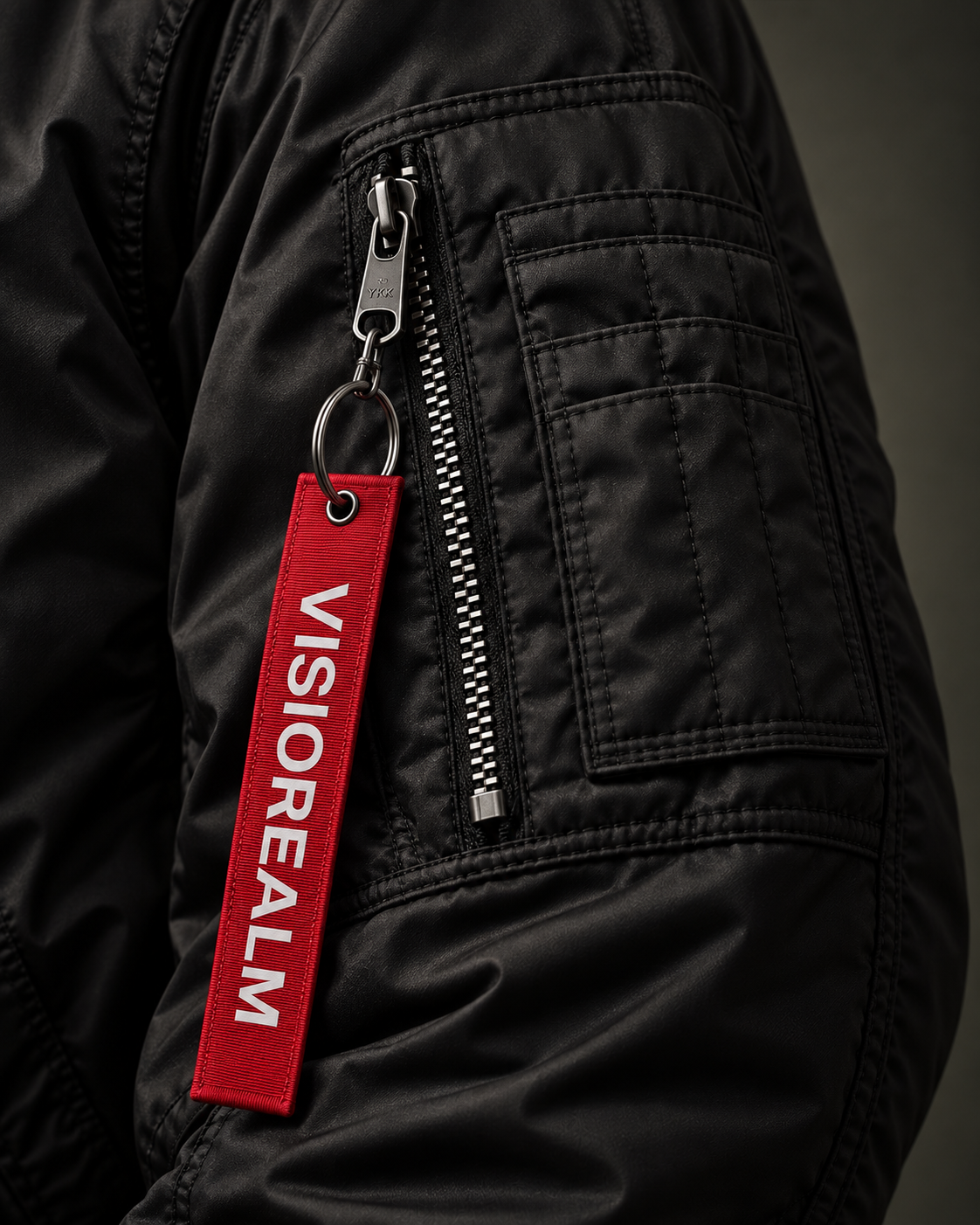 VISIOREALM bomber sleeve utility pocket and red woven zip tag close up